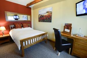 アットルバラにあるOld Field Barn Luxury B & Bのベッドルーム(ベッド1台、デスク、テレビ付)