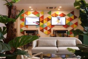 a living room with a couch and two televisions on a wall at Casa Andina Standard Benavides in Lima