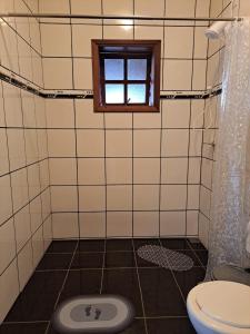 a bathroom with a toilet and a window at Quarto confortável em Diamantina in Diamantina