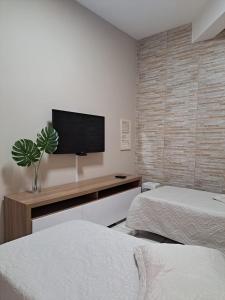 a bedroom with two beds and a flat screen tv at Quarto confortável em Diamantina in Diamantina