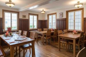 a restaurant with wooden tables and chairs and windows at Pension Pauserei in Oedheim
