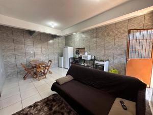 a living room with a couch and a kitchen with a table at Kit Net 01 Viamão in Viamão
