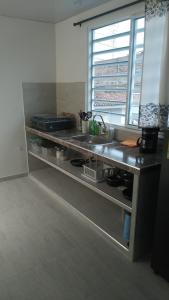 a kitchen with a counter with a sink and a window at Buga home in Buga