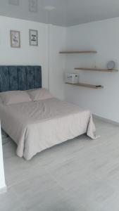 a white bedroom with a bed with a blue headboard at Buga home in Buga