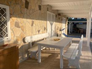 Una mesa blanca y sillas en un patio con una pared de piedra. en Rifugio di campagna, en Varcaturo