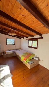 a room with two beds in a room with wooden ceilings at Cabaña de montaña con pileta en hermoso predio in Villa Yacanto