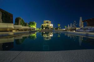 a swimming pool at night with a house in the background at Niovi Boutique Apartments in Afitos