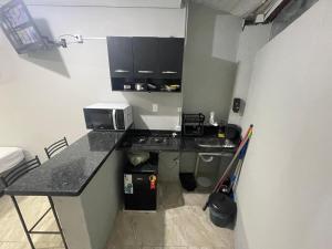 a small kitchen with a sink and a microwave at Cantinho Fátima - Kitnet aconchegante próximo ao Santuário Nacional in Aparecida +6 photos