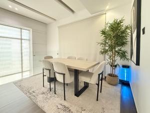 a dining room with a table and chairs and a potted plant at AB Villa - Pool & Cinema in Ajman 