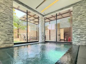 an indoor swimming pool in a room with large windows at AB Villa - Pool & Cinema in Ajman 