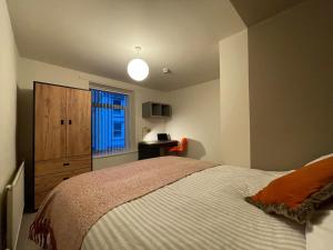 a bedroom with a bed and a dresser and a window at Newly Renovated House in Aberystwyth Town Centre in Aberystwyth