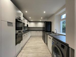 a kitchen with white cabinets and a washer and dryer at Newly Renovated House in Aberystwyth Town Centre in Aberystwyth +5 photos
