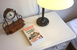a book on a table next to a lamp and a clock at FeWo Zar Ferdinand Schloss Weitersroda in Hildburghausen