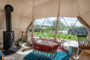 a room with a hammock in a tent with a fireplace at Lakeview Dome in Henfield