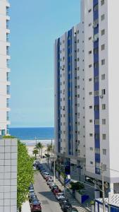 a large building next to a parking lot with a beach at Vida a Beira Mar -Apartamentos com Garagem, Ar Condicionado e Portaria 24h, a 3 Minutos da Praia in Praia Grande