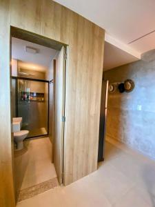a bathroom with a toilet and a glass door at Kauai Beach Residence 403 in Tamandaré