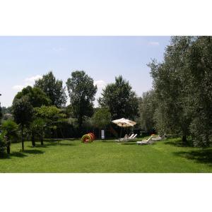 a park with chairs and an umbrella in the grass at Residence Miralago Rooms & Apartments in Manerba del Garda