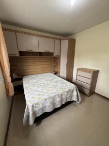 Un dormitorio pequeño con una cama y un armario de madera. en Casa 2 dormitórios, en Passo de Torres