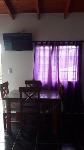 a dining room with a table and purple curtains at Complejo Junior in San Clemente del Tuyu