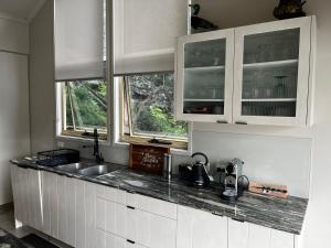 a kitchen with white cabinets and a sink and two windows at Dreamtime Bay 
