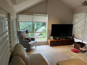 a living room with a flat screen tv and a chair at Dreamtime Bay 