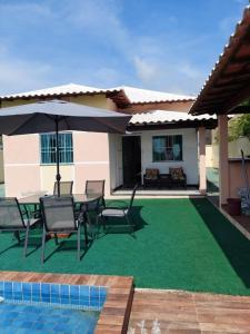 a patio with a table and chairs and an umbrella at Cantinho da família in Araruama