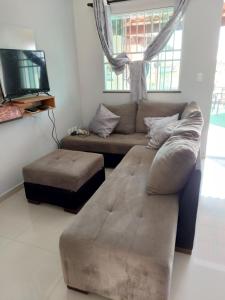 a living room with a couch and a ottoman at Cantinho da família in Araruama