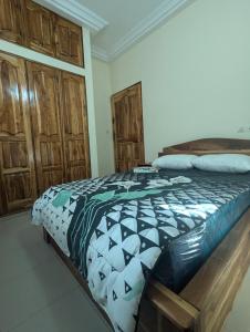 Un dormitorio con una cama y armarios de madera. en Villa Ange Coeur, en Komé