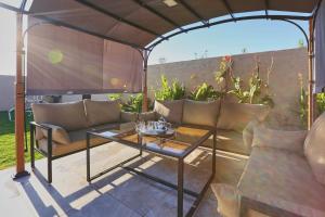 un patio avec une table et des canapés sous une tonnelle dans l'établissement Villa d eden , Private Pool and Hammam, à Azib Oulad Lâdem