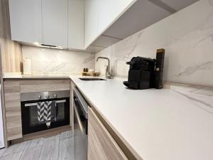 a kitchen with white cabinets and a black appliance at Urban Suites Aluche in Madrid +11 photos