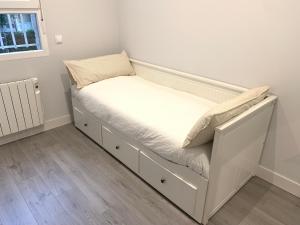 a bedroom with a bed with white sheets and a window at Urban Suites Aluche in Madrid