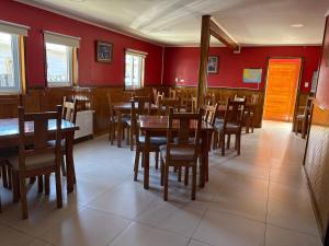 a dining room with red walls and wooden tables and chairs at Hostal America en Puerto Natales in Puerto Natales