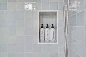 a row of three bottles in a niche in a shower at Steps To Beach! 4 Condos In 1- Perfect For Groups in West Palm Beach +173 photos