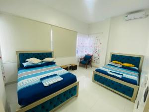 a bedroom with two beds and a chair at Apartamento Ciudad del Surf Montañita in Montañita