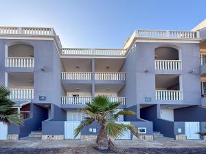 un edificio azul con una palmera delante de él en I LOVE BOA VISTA - Seafront Apartments, en Sal Rei