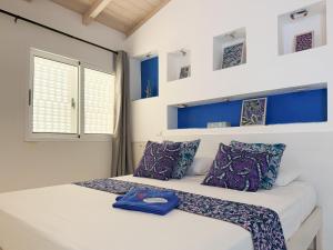 un dormitorio con paredes azules y blancas y una cama con almohadas moradas en I LOVE BOA VISTA - Seafront Apartments, en Sal Rei