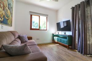 Una sala de estar con un sofá y un televisor de pantalla plana. en House with Beach Access - 2 min Walk, en Florianópolis