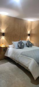 Un dormitorio con una gran cama blanca con dos almohadas. en Departamentos Dragones Puerto Natales, en Puerto Natales