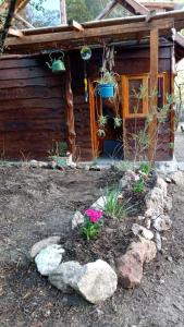a garden in front of a log cabin at Cabaña El Poeta in Cuesta Blanca