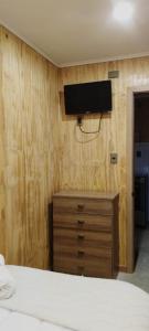 1 dormitorio con tocador y TV en la pared en Departamentos Dragones Puerto Natales, en Puerto Natales