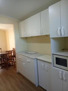 a kitchen with white cabinets and a table and chairs at Cómodo y económico departamento en segundo piso in La Serena