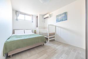 a white bedroom with a bed and a crib at Skytree House Oshiage New 3-story Villa, 2 Showers, 2 Toilets, 4 Rooms, 3 min walk to Oshiage Station in Tokyo
