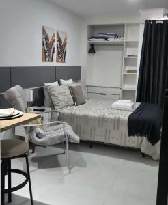 una camera da letto con un letto, un tavolo e una scrivania di Home Easy Flat a Volta Redonda Altre 16 foto