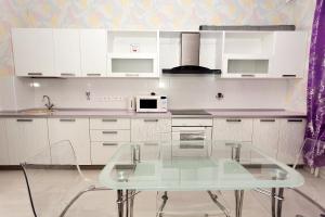 a kitchen with a glass table and a microwave at Apartment Grand Kazan on Chistopolskaya 71 in Kazan