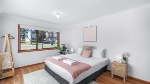 a white bedroom with a bed and a window at King Stingray in Currarong