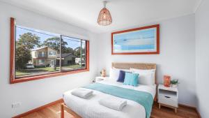 a bedroom with a bed and a large window at King Stingray in Currarong