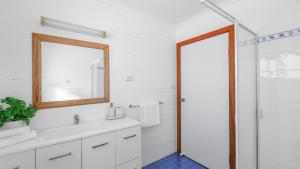 a bathroom with a white sink and a mirror at King Stingray in Currarong +18 photos