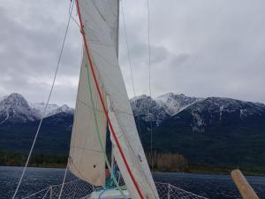 ein Segelboot auf dem Wasser mit Bergen im Hintergrund in der Unterkunft Cabaña La Delfina in Epuyén