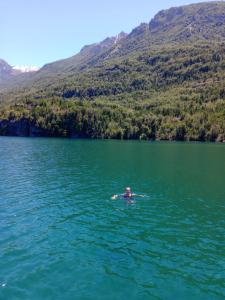 Eine Person schwimmt in einem See vor einem Berg in der Unterkunft Cabaña La Delfina in Epuyén + 1 Foto