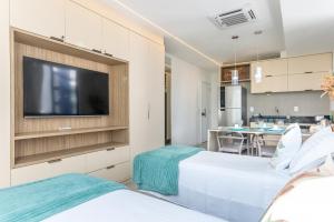 two beds in a room with a flat screen tv at Boa Viagem - FLAT ROOFTOP 470 - NOVO in Recife